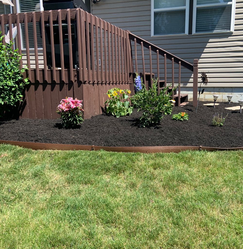Mulched flower bed with fresh plantings beside a deck